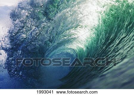 Stock Image - Hawaii, Inside Curling Blue Wave, Sun Shining Through Crest.. Fotosearch