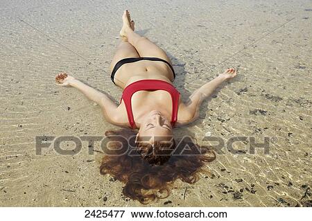 Stock Photo - Hawaii, Kauai, A redheaded woman laying in the water.. Fotosearch