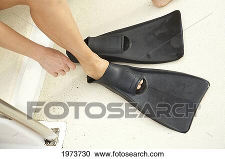 Stock Image - Hawaii, Kauai, A Woman Putting Black Fins On.. Fotosearch