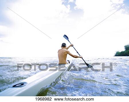 Stock Image - Hawaii, Kauai, Anini Beach, Active Male Paddling In A One Man Canoe.. Fotosearch