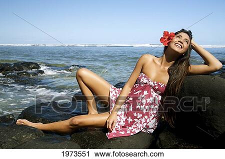 Stock Image - Hawaii, Kauai, Anini Beach, Attractive Young Woman On The Rocks With Hawaiiana Attire.. Fotosearch