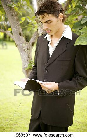 Stock Photo - Hawaii, Kauai, Business Man Reading A Book On A Grassy Field. Fotosearch