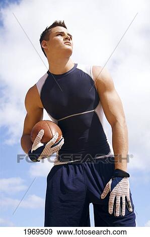 Hawaii, Kauai, Haena Beach, Fit Male Holding A Football With Beautiful Clouds In The Background. View Large Photo Image Stock Photo - Hawaii, Kauai, Haena Beach, Fit Male Holding A Football With Beautiful Clouds In The Background.. Fotosearch