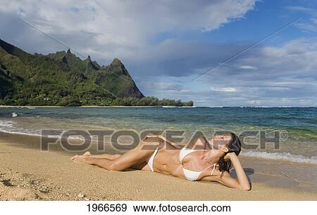 Stock Photo - Hawaii, Kauai, Haena Beach Tunnels Beach, Woman Laying On Sandy Shore.. Fotosearch