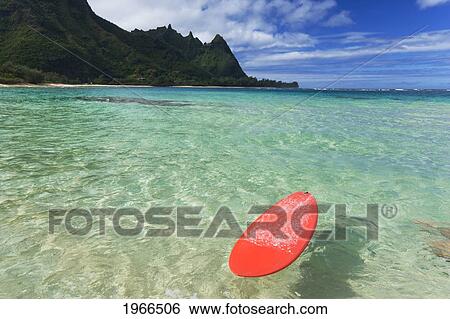 Stock Photograph - Hawaii, Kauai, Haena Beach Tunnels Beach, Red Surfboard Floating In Shallow Ocean.. Fotosearch