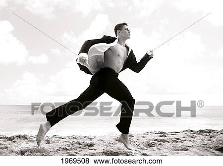 Stock Photo - Hawaii, Kauai, Haena Beach, Young Man Dressed In Business Attire Running On Beach.. Fotosearch