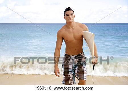 Hawaii, Kauai, Haena Beach, Young Man At The Beach Walking With Surfboard. View Large Photo Image Stock Photograph - Hawaii, Kauai, Haena Beach, Young Man At The Beach Walking With Surfboard.. Fotosearch