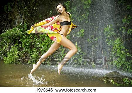 Stock Photograph - Hawaii, Kauai, Haena Falls, Attractive Young Woman On Jumping In The Falls.. Fotosearch