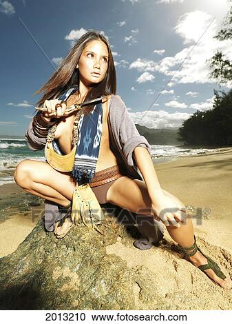 Stock Image - Hawaii, Kauai, Haena, Model Poses With Polynesian Tribal Fashions.. Fotosearch