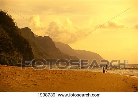 Stock Photo - Hawaii, Kauai, Haena, Na Pali Coast, Couple Exploring Beach At Sunset, Soft Lighting. Fotosearch