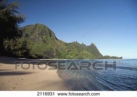 Stock Image - Hawaii, Kauai, Haena, Tunnels Beach, Clear blue water and lush green mountain peaks.. Fotosearch