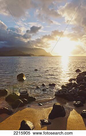 Stock Photography - Hawaii, Kauai, Hanalei Bay, Dramatic sunset over ocean from beach.. Fotosearch