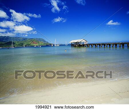 Stock Image - Hawaii, Kauai, Hanalei Bay With Pier Walkway, Sailboats Anchored In Background. Fotosearch