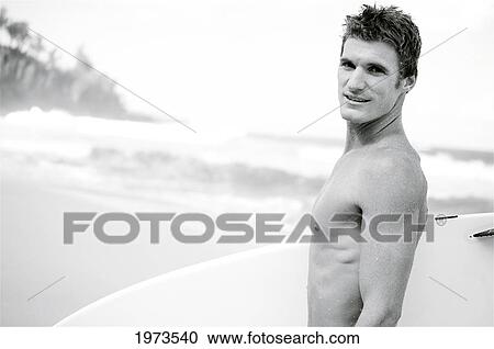 Stock Image - Hawaii, Kauai, Hanalei Bay, Young Man At The Beach Walking With Surfboard.. Fotosearch
