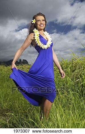 Stock Photo - Hawaii, Kauai, Hanalei, Beautiful Fashion Model On A Grassy Field In A Blue Dress Wearing Plumerias.. Fotosearch