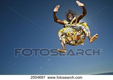 Stock Photo - Hawaii, Kauai, Kealia Beach, African Dancer Leaping In The Air.. Fotosearch