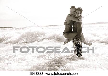 Stock Image - Hawaii, Kauai, Kealia Beach, Beautiful Couple On The Beach Having Fun, Black And White.. Fotosearch