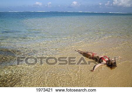 Hawaii, Kauai, Kealia Beach, Woman Laying On The Beach In The Shoreline. View Large Photo Image Stock Image - Hawaii, Kauai, Kealia Beach, Woman Laying On The Beach In The Shoreline.. Fotosearch