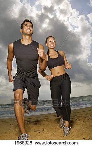 Stock Photo - Hawaii, Kauai, Kealia Beach, Young Fit Couple Jogging On The Beach.. Fotosearch