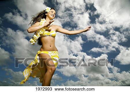 Stock Image - Hawaii, Kauai, Kealia, Beautiful Hawaiian Girl Dancing Hula On Ocean Shoreline.. Fotosearch