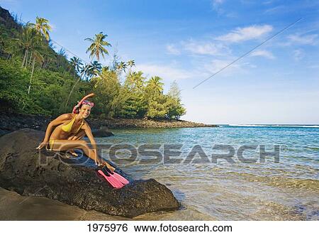 Stock Photograph - Hawaii, Kauai, Kee Beach, Woman With Snorkel Gear Smiling On A Rock.. Fotosearch