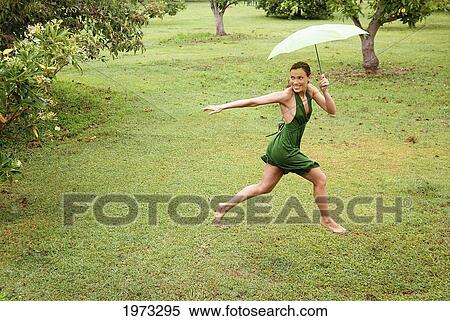 Hawaii, Kauai, Kilauea, Beautiful Fashion Model Running On A Grassy Field Holding An Umbrella. View Large Photo Image Stock Photography - Hawaii, Kauai, Kilauea, Beautiful Fashion Model Running On A Grassy Field Holding An Umbrella.. Fotosearch