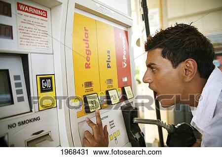 Stock Image - Hawaii, Kauai, Kilauea, Young Man Is Shocked At The Price At A Gas Station.. Fotosearch