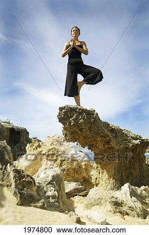 Stock Image - Hawaii, Kauai, Mahaulepu, Woman Doing Yoga.. Fotosearch
