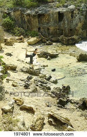 Stock Image - Hawaii, Kauai, Mahaulepu, Woman Doing Yoga.. Fotosearch
