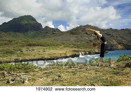 Stock Image - Hawaii, Kauai, Mahaulepu, Woman Doing Yoga.. Fotosearch