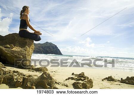 Stock Image - Hawaii, Kauai, Mahaulepu, Woman Doing Yoga.. Fotosearch