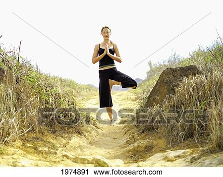 Stock Image - Hawaii, Kauai, Mahaulepu, Woman Doing Yoga.. Fotosearch