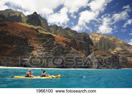 Stock Image - Hawaii, Kauai, Na Pali Coast, Couple Kayaking Along Sea Cliffs. Editorial Use Only.. Fotosearch