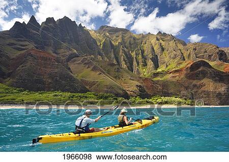Hawaii, Kauai, Na Pali Coast, Couple Kayaking Along Coastline, Beautiful Mountain Ridges In Background. Editorial Use Only. View Large Photo Image Stock Photo - Hawaii, Kauai, Na Pali Coast, Couple Kayaking Along Coastline, Beautiful Mountain Ridges In Background. Editorial Use Only.. Fotosearch
