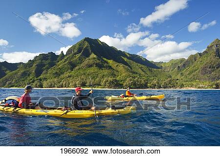 Stock Image - Hawaii, Kauai, Na Pali Coast, Group Of Kayakers Paddling Along Coastline, Beautiful Mountains In Background. Editorial Use Only.. Fotosearch