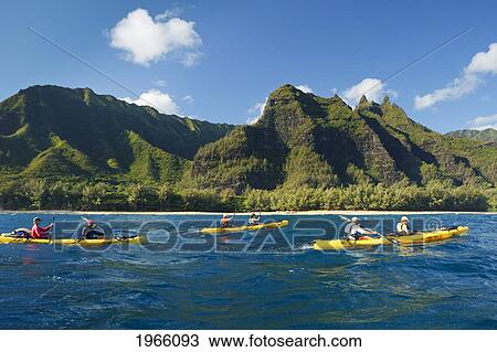 Stock Image - Hawaii, Kauai, Na Pali Coast, Group Of Kayakers Paddling Along Coastline, Beautiful Mountains In Background. Editorial Use Only.. Fotosearch
