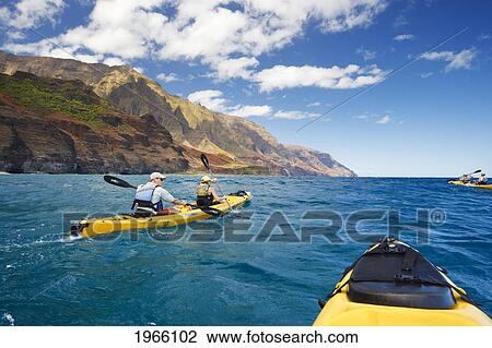 Stock Image - Hawaii, Kauai, Na Pali Coast, Group Of Kayakers Paddling Along Coastline, Beautiful Mountain Ridges In Background. Editorial Use Only.. Fotosearch
