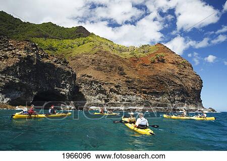 Stock Photograph - Hawaii, Kauai, Na Pali Coast, Group Of Kayakers Paddling Along Coastline, Cliffs And Sea Cave In Distance. Editorial Use Only.. Fotosearch