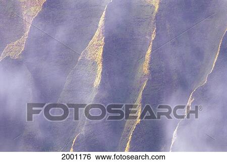 Stock Photograph - Hawaii, Kauai, Na Pali Coast, Kalalau Valley, Pali Cliffs Rugged Detail Through Misty Clouds Sunlight Filter Mountain. Fotosearch