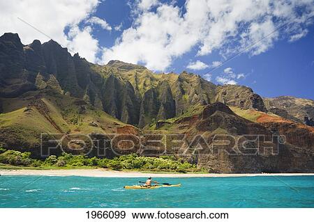 Stock Photo - Hawaii, Kauai, Na Pali Coast, Man Kayaking Along Coastline, Beautiful Mountain Ridges In Background. Editorial Use Only.. Fotosearch