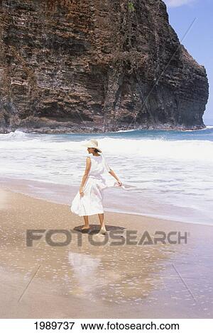 Hawaii, Kauai, Napali Coast, Girl In White Dress And Hat Walks Along The Shoreline. View Large Photo Image Stock Photo - Hawaii, Kauai, Napali Coast, Girl In White Dress And Hat Walks Along The Shoreline.. Fotosearch