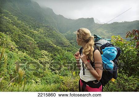Stock Image - Hawaii, Kauai, Napali Coast, Woman Hiking on the Napali Coast Trail.. Fotosearch