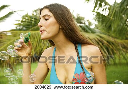 Stock Image - Hawaii, Kauai, North Shore, Brunette Model Blows Bubbles Outside.. Fotosearch