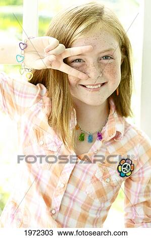 Stock Image - Hawaii, Kauai, North Shore, Girl With Freckles Smiles And Shows A Peace Sign.. Fotosearch