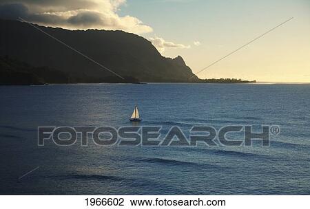 Stock Image - Hawaii, Kauai, North Shore, Hanalei Bay, Haena, Sailboat Illuminated By Afternoon Sunlight.. Fotosearch