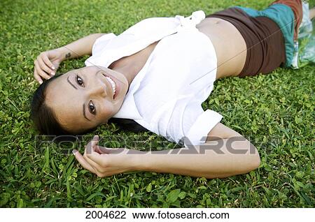 Stock Image - Hawaii, Kauai, North Shore, Model Poses Laying In Grass.. Fotosearch