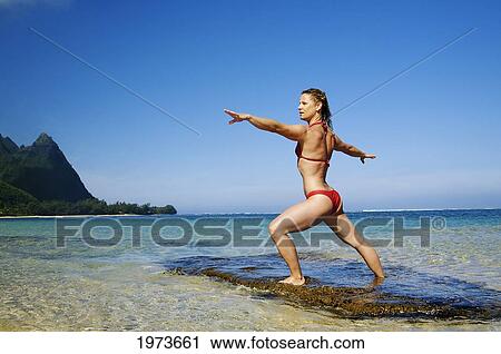 Stock Image - Hawaii, Kauai, North Shore, Tunnels Beach, Woman Doing Yoga.. Fotosearch