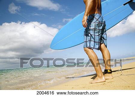 Stock Photograph - Hawaii, Kauai, North Shore, Young Male Checks Out Waves From The Beach.. Fotosearch
