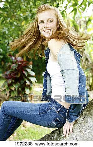Stock Photo - Hawaii, Kauai, North Shore, Young Woman With Red Hair And Freckles Sits On A Palm Tree Outside.. Fotosearch