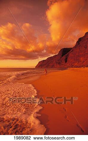 Stock Image - Hawaii, Kauai, Polihale State Park Beach At Sunset, Back View Of Woman Walking Along The Shoreline.. Fotosearch